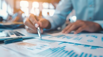 Close-up of a person analyzing financial charts and graphs with a pen and a laptop, highlighting data analysis, financial planning, and business strategy..