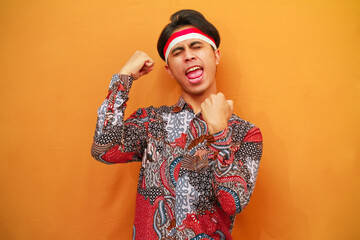 Indonesian man in Batik shirt celebrating Indonesian Independence Day on August 17 concept, posing screaming proud and celebrating victory and success very excited,cheering emotion