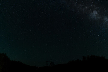 Fototapeta premium Starry night sky with Milky Way above an observatory silhouette.