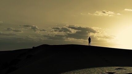 Serene Silhouette of a Person Standing on a Majestic Sand Dune at Dusk