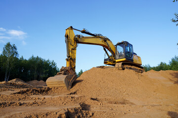 Excavator on earthmoving. Open-pit mining. Backhoe dig sand, ground in quarry. Heavy construction equipment on excavation on construction site. Excavator on groundwork, foundation. Road construction.