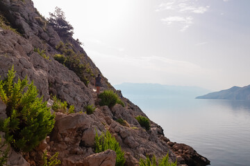 Hiker woman on coastal hiking trail along rocky cliffs overlooking calm Adriatic sea near Baska,...