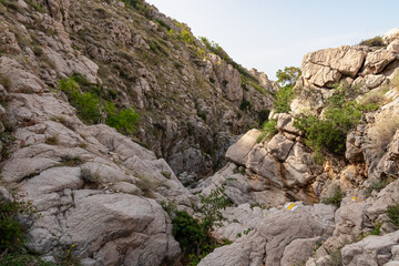 Narrow, rocky gorge Vrzenica (Žig Vrženica) cuts through rugged landscape in Baska, Krk Otok, Primorje-Gorski Kotar, Croatia. Scenic hiking trail through dramatic canyon leading to Vela and Mala Luka