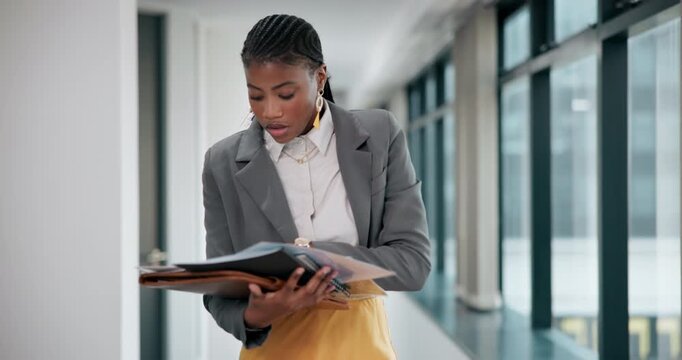 Black woman, walking and watch with documents for deadline, rush or schedule in office building. Young African or stressed business employee checking time on wristwatch with paperwork at workplace