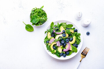 Мegan salad with blueberry, avocado, onion, spinach and arugula, white background, top view