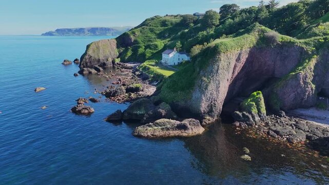 Aerial video of The Cushendun Caves on the Irish Sea Co Antrim Northern Ireland