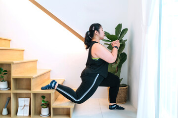 fat exerciser workout using stairs indoors living room single leg lunge. overweight determined...