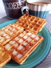 Breakfast with coffee and Belgian waffles on a blue plate.