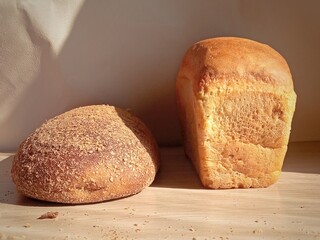 A loaf of white bread and dark bread on the table. Background, place for text. Bread in the store. Bakery. Bakery products. Food. Farm. Comparison of bread made from different types of flour.
