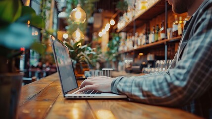 Business professional working on laptop at a wooden bar in a modern cafe, focusing on digital marketing strategies and data processing for effective online business management