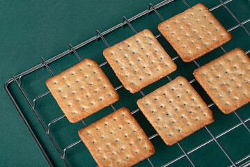 Soda crackers on table with green background, garnished with sesame seeds, healthy breakfast