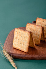 Soda crackers on table with green background, garnished with sesame seeds, healthy breakfast