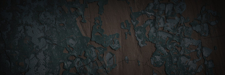 Dark wide panoramic background. Peeling paint on a concrete wall. Dark grunge texture of old cracked flaking paint. Weathered rough painted surface. Patterns of cracks. Darkness background for design.