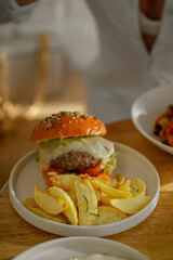 Juicy burger with melted cheese, served with golden fries on a white plate