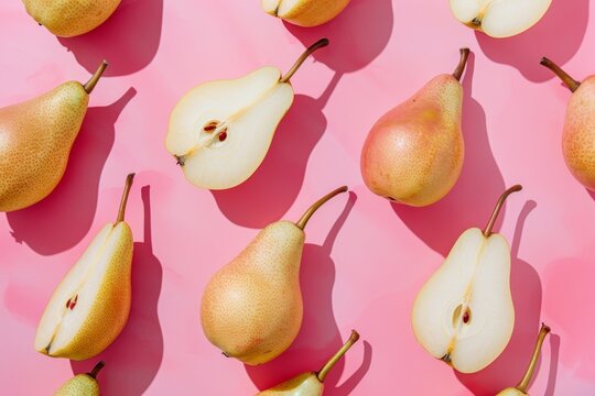 Halved and whole pears arranged on pink background