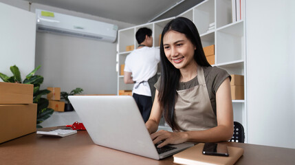 Couple Working Together in Home Office for Their Online Business with Laptops and Packaging Boxes