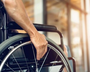A hand rests on the wheel of a wheelchair. AI.