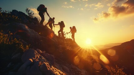 Fototapeta premium A group of hikers silhouetted against a bright sunrise, with one person reaching out to help another climb a rocky slope. 