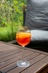 Aperol spritz cocktail in wine glass on a wooden table in the garden.