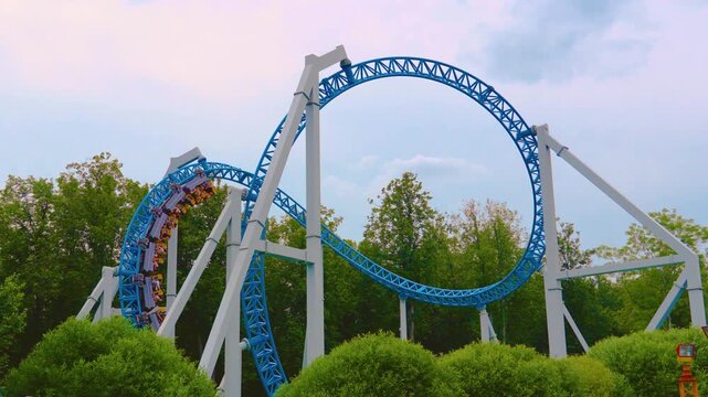 Loop metal frame of a roller coaster in an amusement park. Roller coaster cart with people riding it goes through a loop upside down