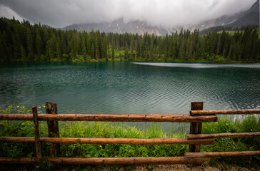Tranquil Lake Surrounded By Dense Forest Under Cloudy Skies During Early Morning Hours