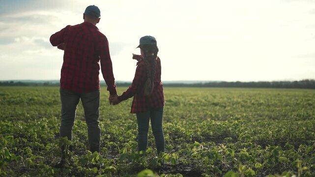 Family farmer agribusiness field. Father and daughter holding hands in field, learning agribusiness at sunset. Family bonding over agribusiness. Teaching next generation about farming. family moment.