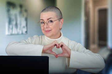 Positive and Inspiring Cancer Survivor in Her 60s Creates Heart Shape with Hands, Radiating Warmth and Optimism.