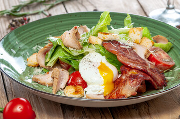 Caesar salad in the author's presentation on a green plate on a wooden background, macro photo