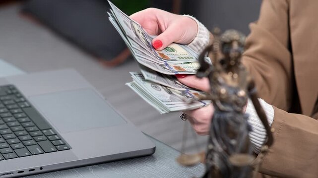 Scales of justice, money, and a laptop at a lawyer&rsquo;s desk. Perfect for illustrating themes of injustice, imbalance, corruption, and legal fees in a professional legal setting.