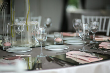 A minimalist and elegant wedding table setting with soft pink accents and crystal glassware