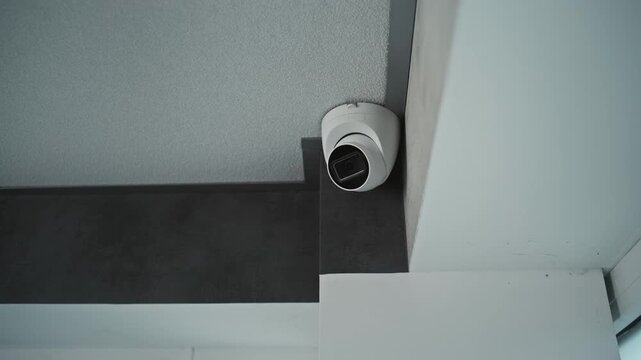 Close up shot of installed CCTV camera hanging on the ceiling in the room of the office building. Modern monitoring and tracking technologies. Security system, video surveillance and privacy concept.