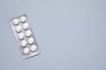 Antibiotic pills in blister on gray background, top view. Space for text