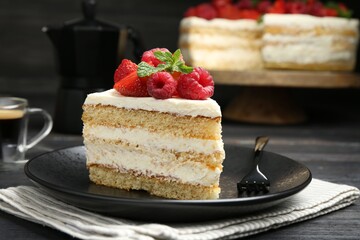 Piece of tasty sponge cake with fresh berries and mint served on black wooden table, closeup