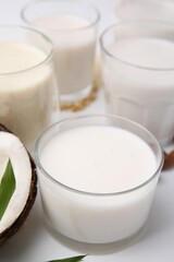 Different types of vegan milk on white table, closeup