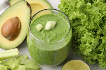 Tasty green smoothie in glass and products on white table, closeup