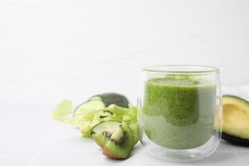 Delicious green smoothie and ingredients on white table. Space for text