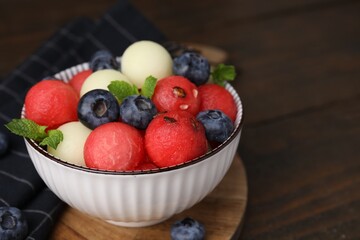 Tasty watermelon and melon balls with blueberries in bowl on wooden table, closeup