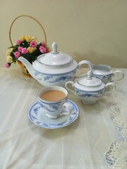 Cup of tea with tea set on a white table cloth.