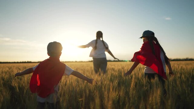 Group children in superhero capes run. Superhero adventure in golden field. Child imagination and play. Group children play superhero. Joyful child moments in nature. Superhero fun for group children.