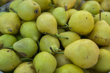 Yellow pears in a basket on the counter of a farmers market.