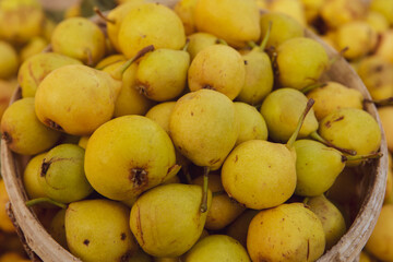 Yellow pears in a basket on the counter of a farmers market.
