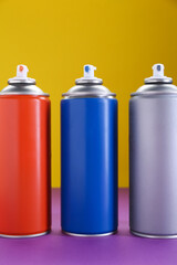 Many spray paint cans on color background