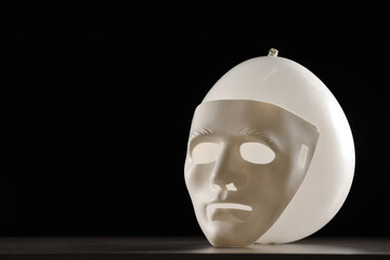 Theatrical performance. Plastic mask and white balloon on table against black background, space for...