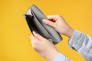Woman with empty wallet on orange background, closeup
