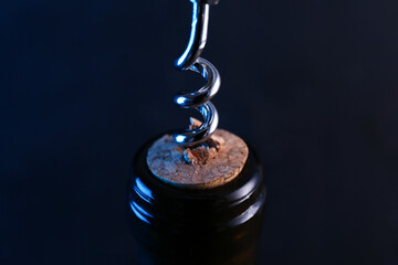 Wine bottle with corkscrew on dark background, closeup