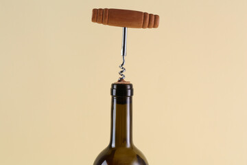 Wine bottle with corkscrew on beige background