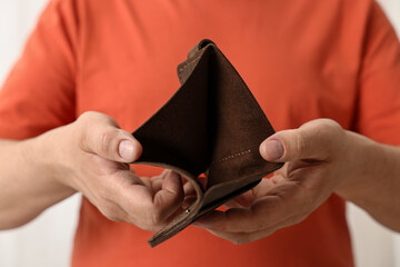 Man with empty wallet on blurred background, closeup