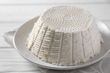 Tasty ricotta (cream cheese) on white wooden table, closeup