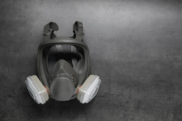 One full face respirator on dark textured table, top view. Space for text © New Africa