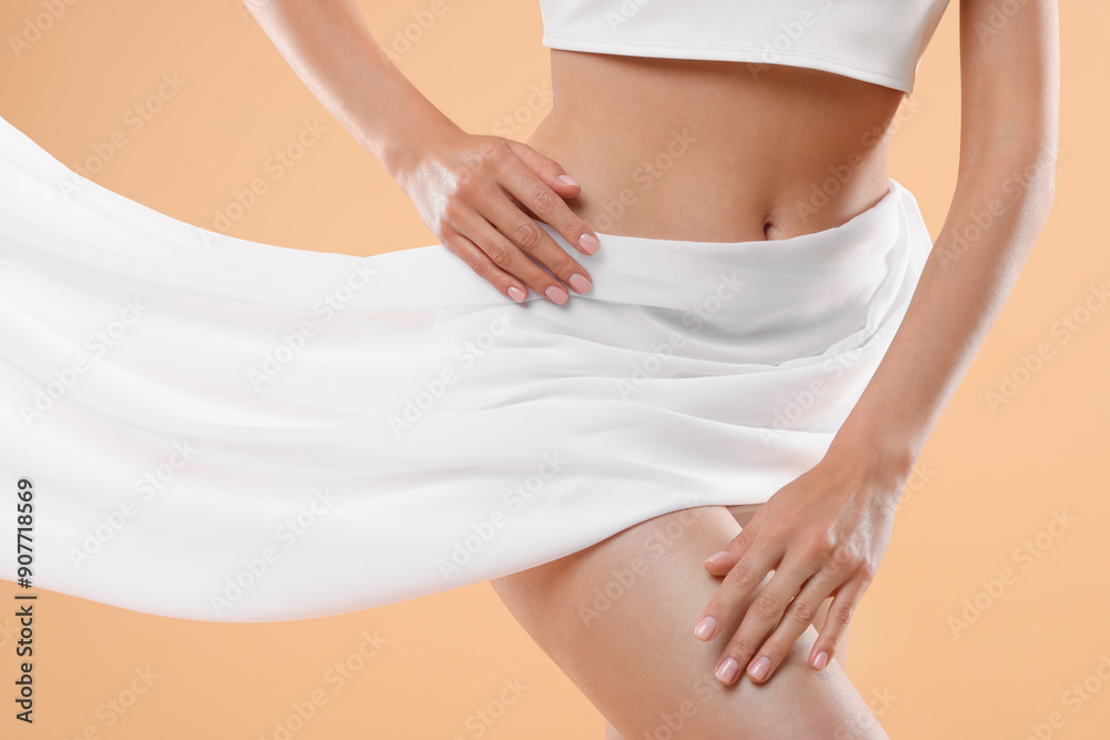 Wall mural Diet and weight loss concept. Woman covering her slim body with silk fabric against beige background, closeup